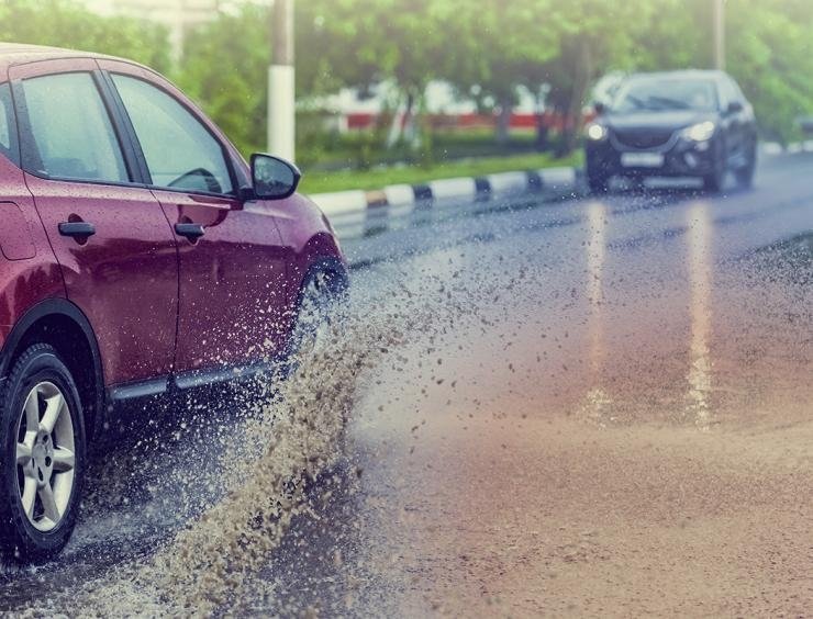 um carro vermelho a percorrer uma estrada molhada